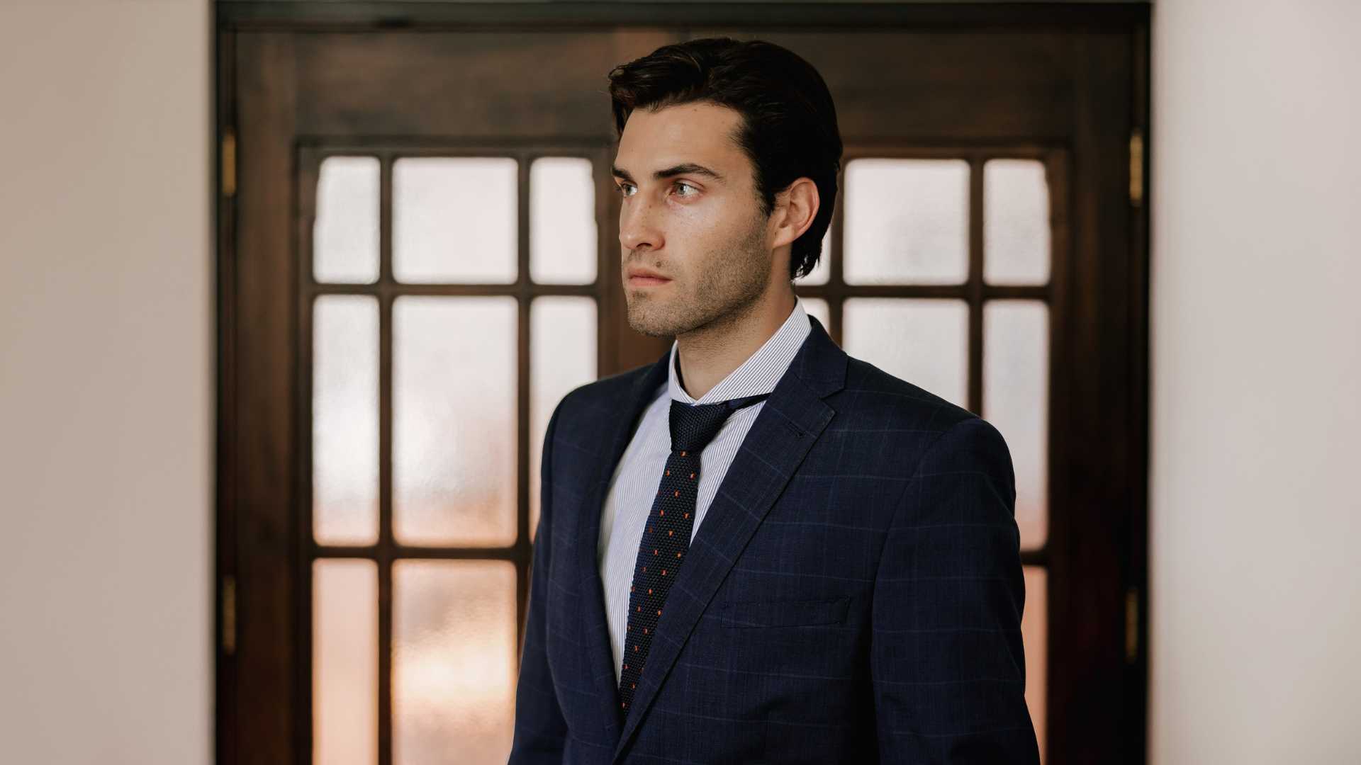 Close up of model wearing extreme cutaway collar shirt in blue stripe with a navy suit and with a tie