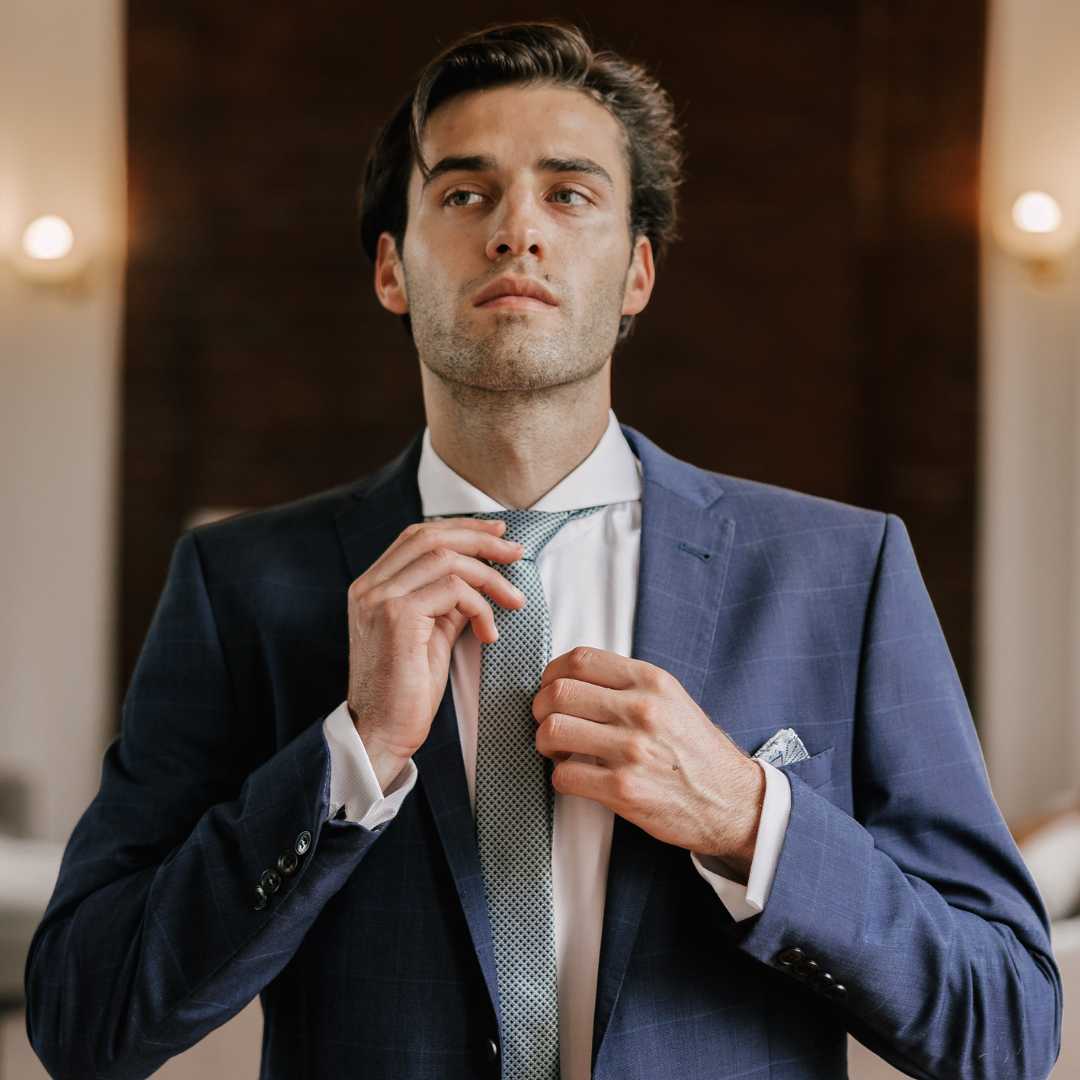 Model wearing navy suit with white extreme cutaway collar dress shirt paired with tie